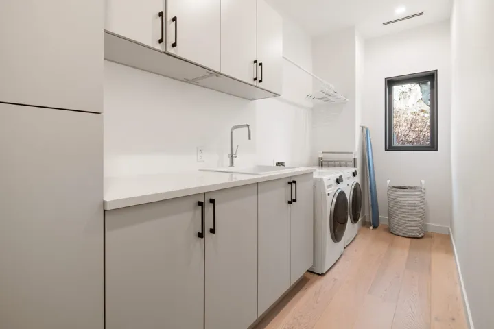 Washroom featuring baseboards, separate washer and dryer, a sink, light wood-style floors, and cabinet space