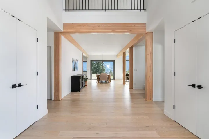 Hallway featuring a high ceiling, light wood-style flooring, and baseboards