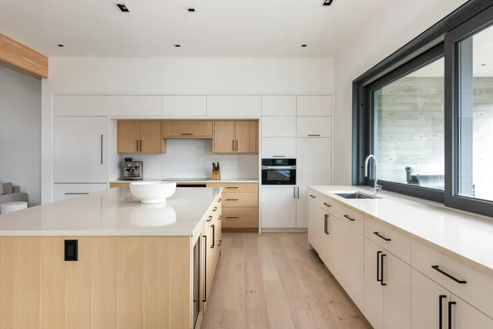 Kitchen with light countertops, oven, backsplash, a sink, and light wood finished floors