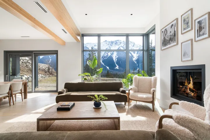 Living room featuring a lit fireplace, a wealth of natural light, visible vents, and beamed ceiling