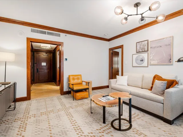Living area featuring a chandelier, baseboards, ornamental molding, and visible vents