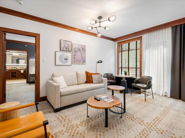 Living room featuring ornamental molding, baseboards, a notable chandelier, and light carpet