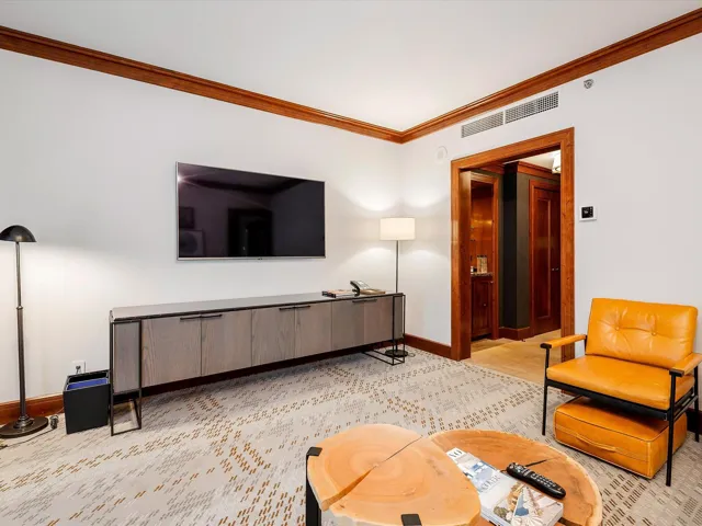 Living area with crown molding, visible vents, and baseboards
