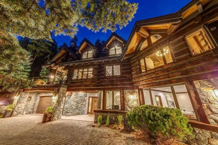 Log home featuring stone siding and decorative driveway