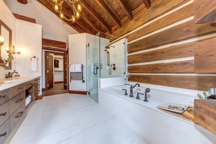 Full bathroom with double vanity, a garden tub, a shower stall, a wood ceiling with exposed beams, and high vaulted ceiling