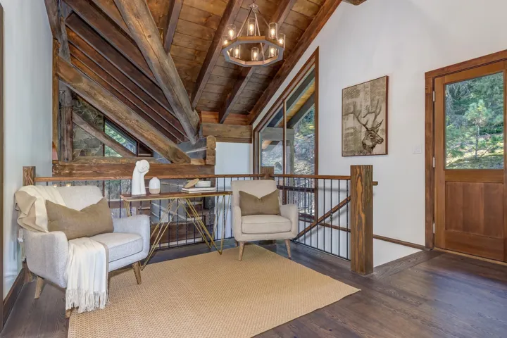 Sitting room with an upstairs landing, dark wood finished floors, healthy amount of natural light, wooden ceiling, and a chandelier
