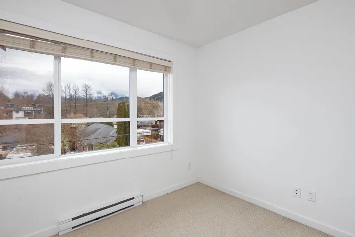 Carpeted empty room featuring plenty of natural light, a baseboard heating unit, and baseboards