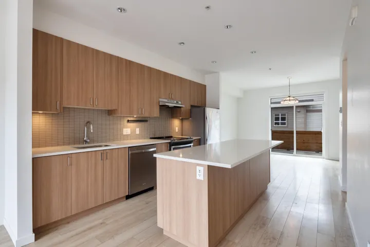 Kitchen featuring under cabinet range hood, decorative backsplash, appliances with stainless steel finishes, modern cabinets, and a sink