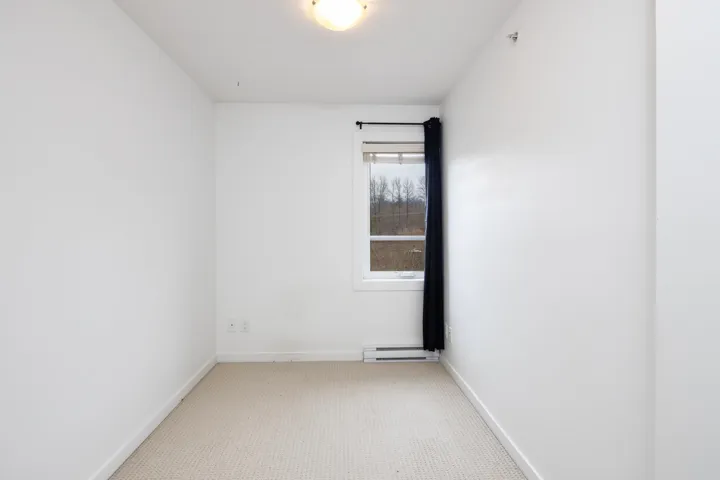 Empty room with carpet flooring, baseboards, and a baseboard radiator