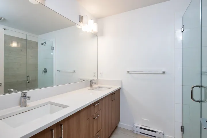 Full bathroom featuring a sink, a shower stall, double vanity, and a baseboard radiator