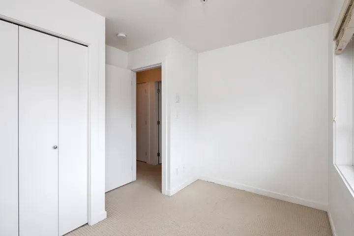 Unfurnished bedroom with a closet, light colored carpet, and baseboards
