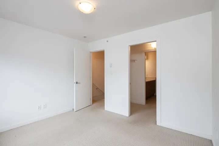 Unfurnished bedroom featuring a walk in closet, baseboards, a closet, and light carpet