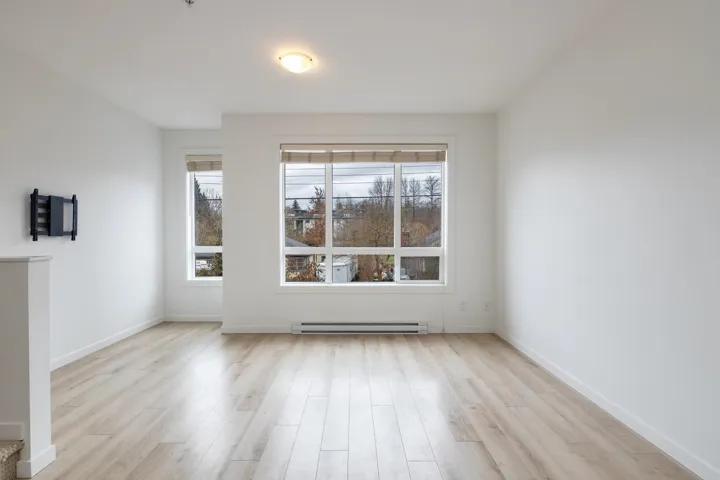 Unfurnished room featuring a baseboard radiator, baseboards, and light wood finished floors