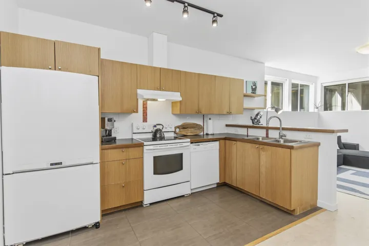Kitchen featuring wood-finish cabinetry, white appliances, and track lighting