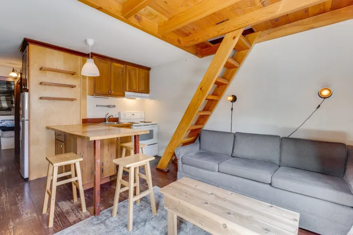 Kitchen with white range with electric cooktop, under cabinet range hood, freestanding refrigerator, and dark wood finished floors