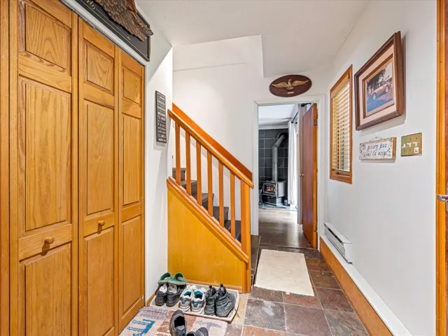 Hall featuring baseboard heating, stairs, and stone tile floors