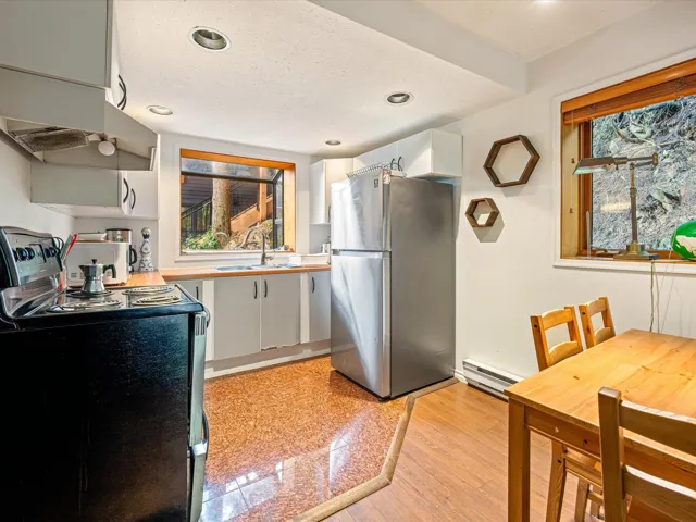 Kitchen featuring freestanding refrigerator, black electric range, recessed lighting, white cabinetry, and a baseboard heating unit