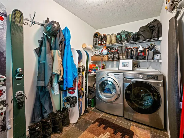 Washroom featuring independent washer and dryer, a textured ceiling, and stone tile flooring