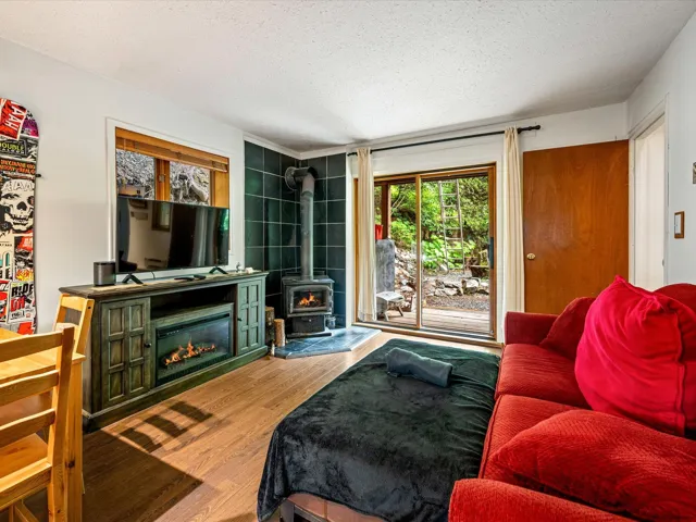 Living room featuring wood finished floors, a textured ceiling, and a wood stove