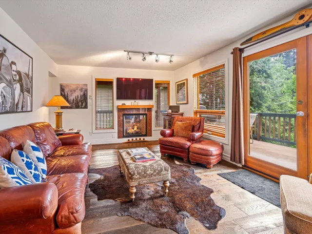 Living area featuring a textured ceiling, wood finished floors, and a glass covered fireplace