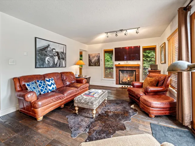 Living room featuring hardwood / wood-style flooring, a warm lit fireplace, and a textured ceiling