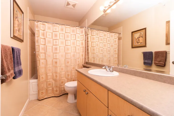 Bathroom with shower / bath combo, vanity, and light tile patterned flooring