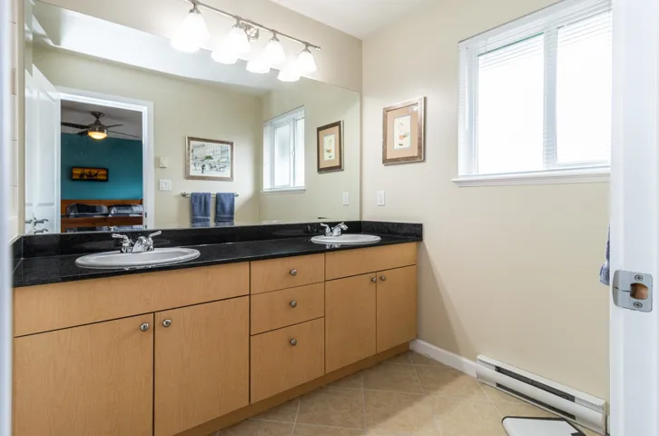 Full bath featuring a baseboard radiator, double vanity, light tile patterned floors, a ceiling fan, and ensuite bathroom