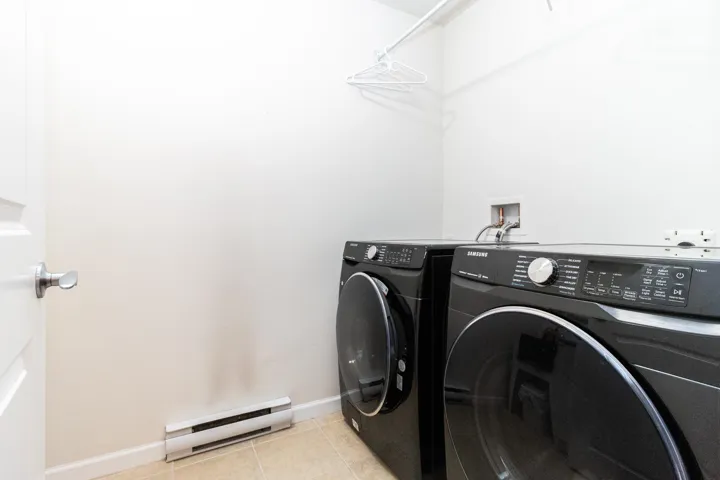 Laundry area featuring a baseboard heating unit, light tile patterned floors, and independent washer and dryer