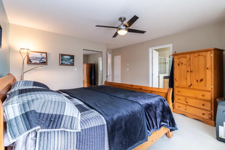 Bedroom featuring ceiling fan, light colored carpet, connected bathroom, and a closet