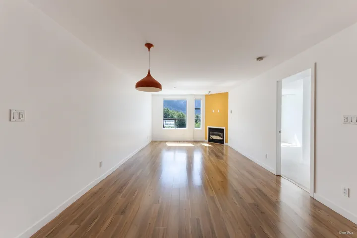 Unfurnished living room with wood finished floors, a glass covered fireplace, and baseboards