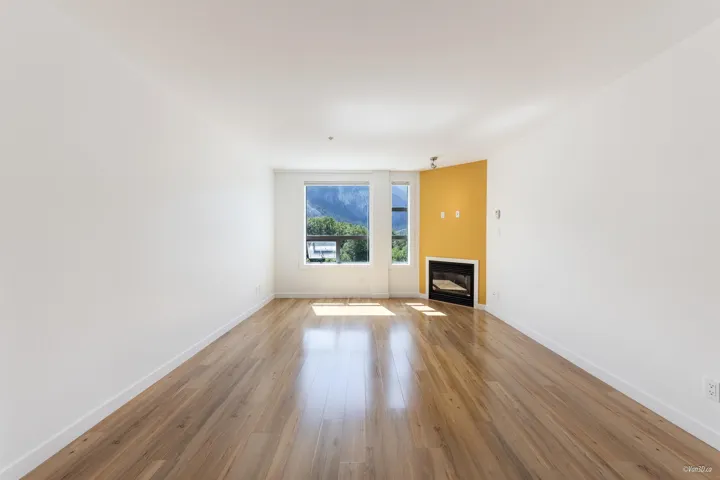 Unfurnished living room with baseboards, light wood-style flooring, and a glass covered fireplace