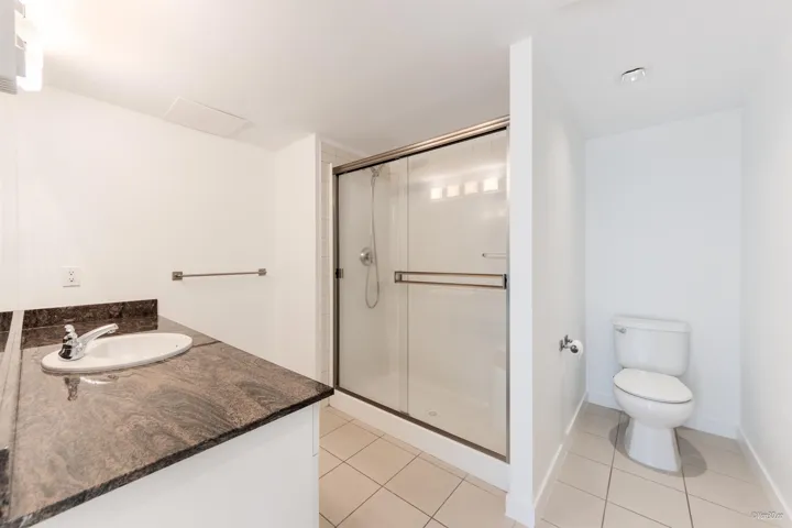Full bathroom featuring tile patterned flooring, a stall shower, vanity, toilet, and baseboards