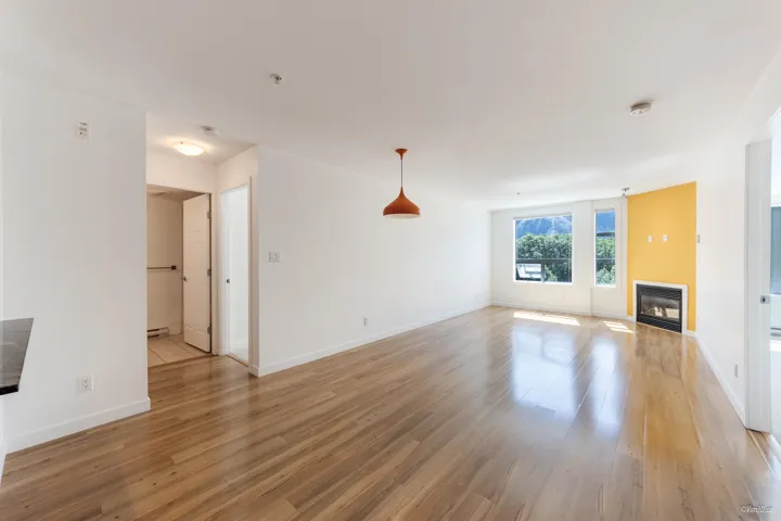 Unfurnished living room with heating unit, light wood finished floors, baseboards, a glass covered fireplace, and a baseboard heating unit