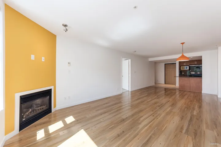 Unfurnished living room with a glass covered fireplace, light wood finished floors, and baseboards