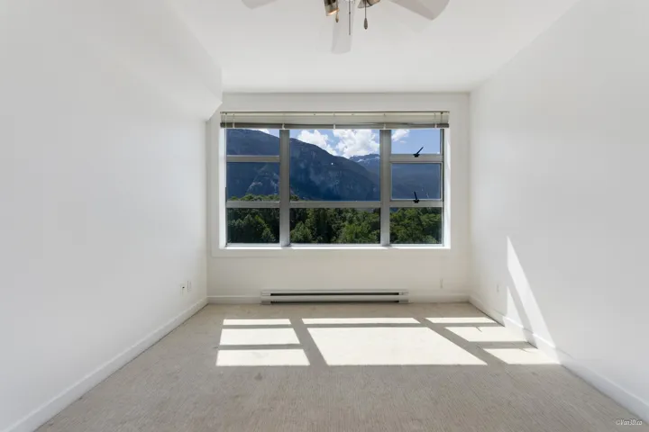 Carpeted spare room with a baseboard heating unit, ceiling fan, a mountain view, and baseboards