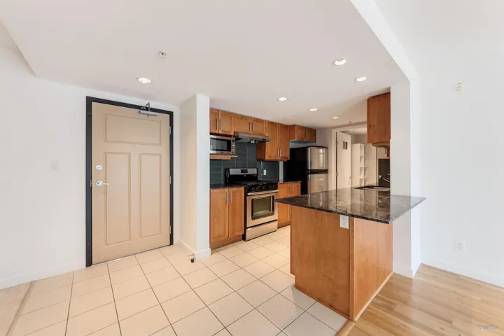 Kitchen with appliances with stainless steel finishes, baseboards, a peninsula, tasteful backsplash, and recessed lighting