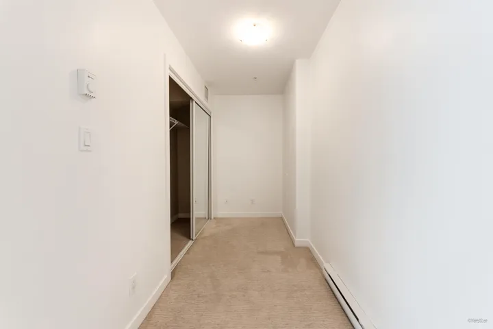 Hallway featuring light carpet and baseboards