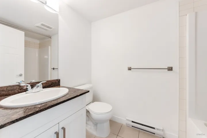 Bathroom featuring a baseboard radiator, a shower, vanity, and toilet
