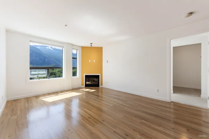 Unfurnished living room with light wood-style flooring, a glass covered fireplace, and baseboards