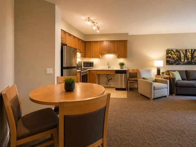 Open-concept living space featuring a full kitchen with wood cabinetry, stainless steel appliances, and a built-in dishwasher