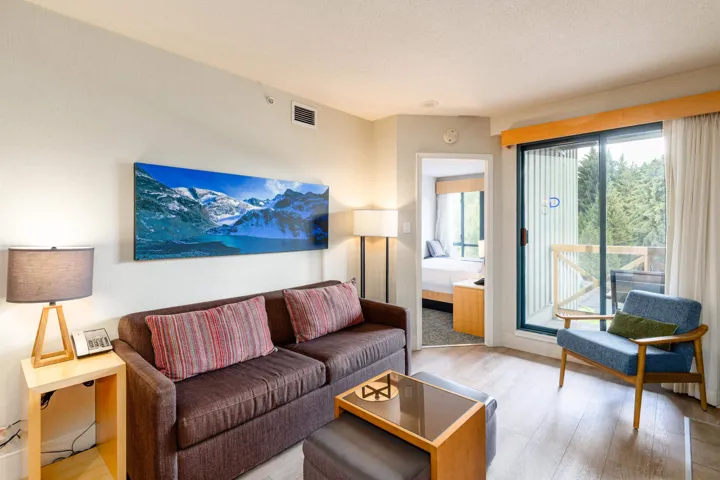 Living area featuring wood-finish flooring, a sliding glass door providing outdoor access, and a sightline into an adjacent room