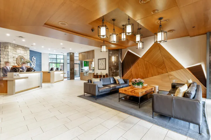 Lobby featuring a wood-panel ceiling, stone accent walls, and a geometric wood feature wall with backlighting