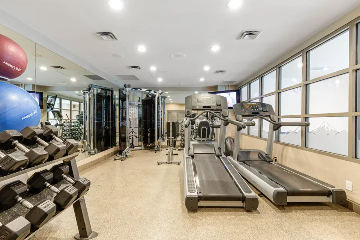 Dedicated fitness space featuring ample natural light, recessed ceiling lighting, a mirrored wall, and specialized flooring