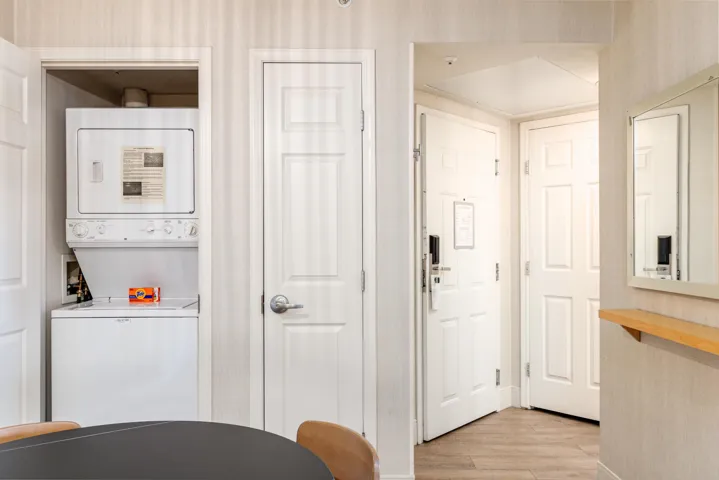 Dedicated laundry closet featuring a stacked white washer and dryer unit