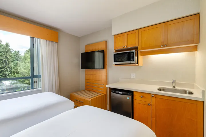 Integrated kitchenette featuring a stainless steel microwave, compact refrigerator, and undermount sink