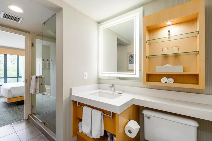 Bathroom featuring a modern vanity with an integrated sink, illuminated mirror, and a glass-enclosed shower
