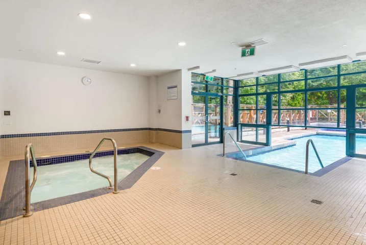 Indoor aquatic area featuring a large spa and a swimming pool with integrated steps