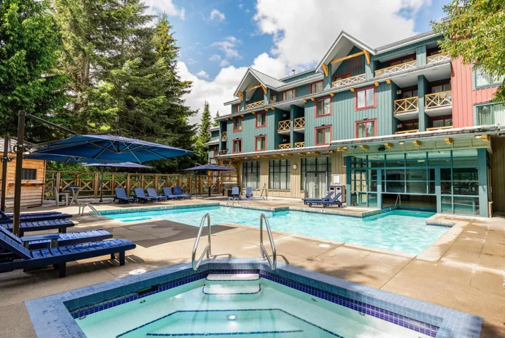 Resort-style outdoor area featuring a swimming pool, integrated hot tub with blue tile accents, and concrete decking