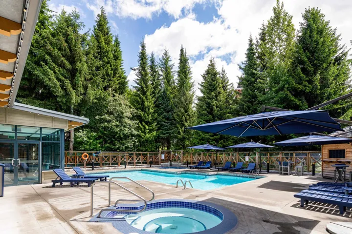 Outdoor swimming pool with integrated spa and surrounding concrete decking