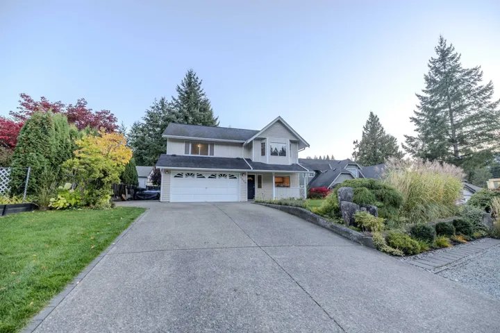 Traditional-style home featuring concrete driveway, a garage, and a front lawn